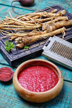 Wooden bowl with seasoning prepared from the fresh roots of horseradish