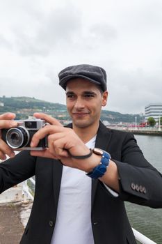 Modern younger  shooting through his vintage film camera in a cloudy day