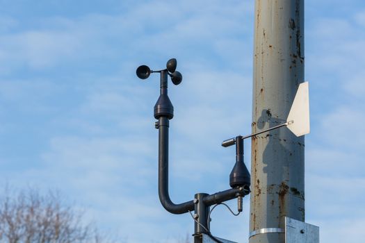 Weather station with anemometer on blue sky.