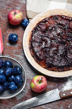 Apple pie with apples and plums in rustic style