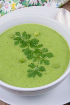 A plate of soup puree of green peas with parsley on a table