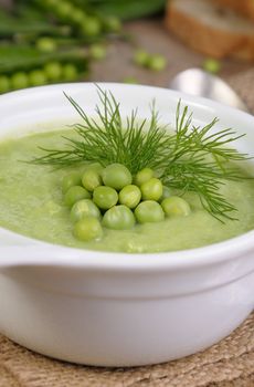A plate of soup puree of green peas with dill on a table