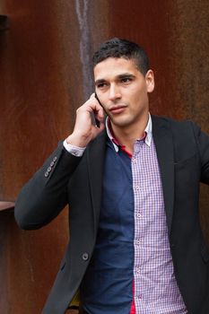 Young arab man talking on the phone next to a oxide wall