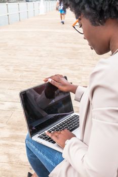Modern African woman working outdoors with her laptop