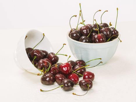 Photo of two bowls of wet cherries over white background.