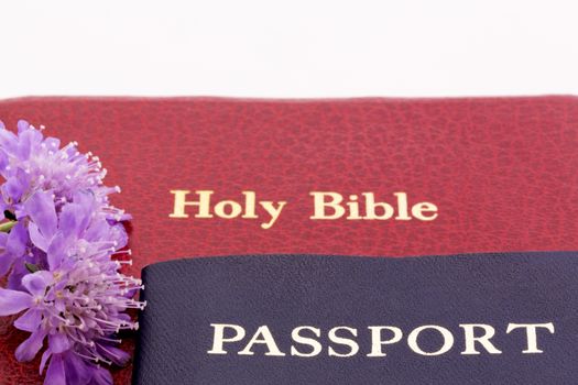 Red bible with dark passport and purple blossoms reflect successful Christian travel and international business