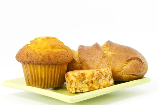 Healthy presentation of fresh corn muffin with rustic bread and cheddar cheese on square, modern light green plate