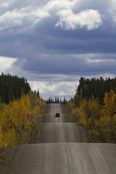 Driving the rippling hills of Cassiar-Stewart Highway in British Columbia creates adventurous, rambling metaphor. Vertical image with copy space in sky. 