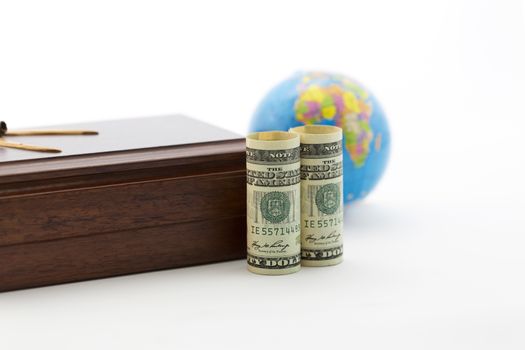 Handsome wood box and American currency in foreground with soft focus on blue globe in background.  Business travel, security, and investment reflected. 