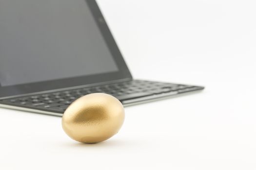Gold nest egg in front of keyboard and screen electronics reflects investment in technology sector to build retirement funds