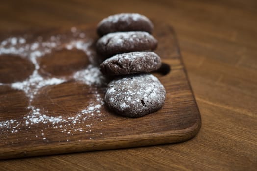 chocolate cookies with sugar powder on wooden kitchen Board