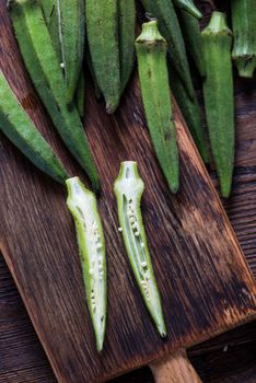 Farm fresh okra on wooden board, whole and sliced