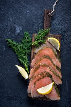 Smoked salmon on wooden board with dil and lemon from above