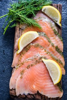 Smoked salmon on wooden board with dil and lemon from above