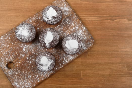 chocolate muffins with white icing lying on a Board sprinkled with powdered sugar