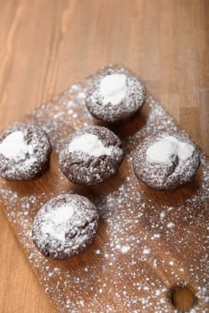 chocolate muffins with white icing lying on a Board sprinkled with powdered sugar