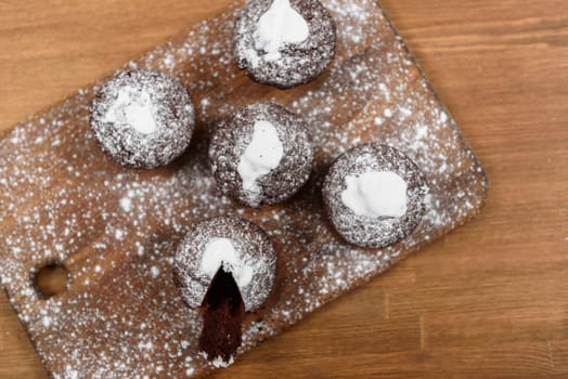 chocolate muffins with white icing lying on a Board sprinkled with powdered sugar