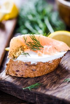 Fresh bread cottage cheese and smoked salmon with dill on wooden serving board