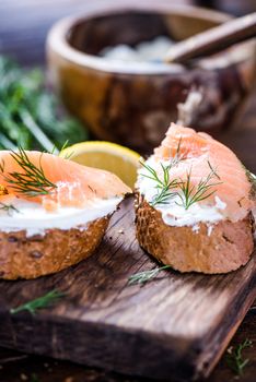 Fresh bread cottage cheese and smoked salmon with dill on wooden serving board