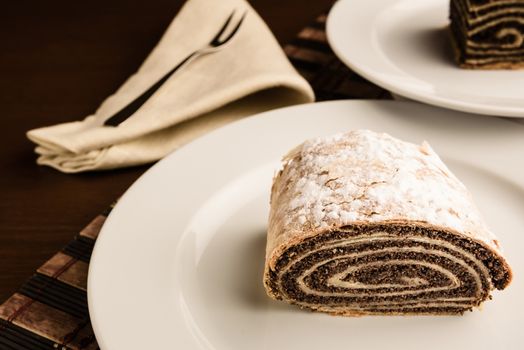 strudel with poppy seeds on a ceramic white plate on wooden background