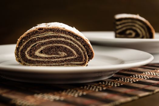 strudel with poppy seeds on a ceramic white plate on wooden background