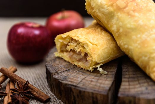 Apple strudel on wooden end of a tree with apples, cinnamon and star anise