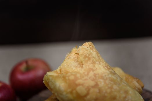 Apple strudel on wooden end of a tree with apples, cinnamon and star anise