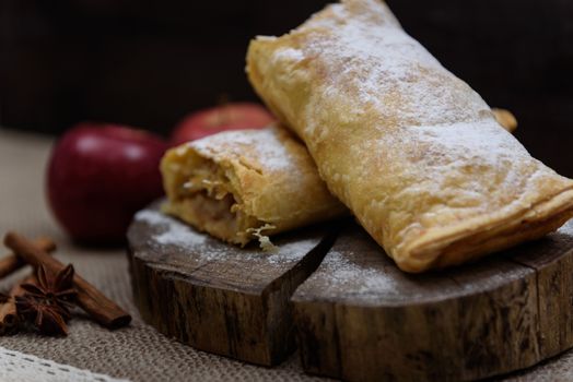 Apple strudel on wooden end of a tree with apples, cinnamon and star anise