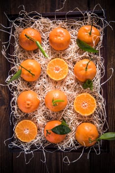 Tangerines in wooden rustic crate from above, whole and half cut