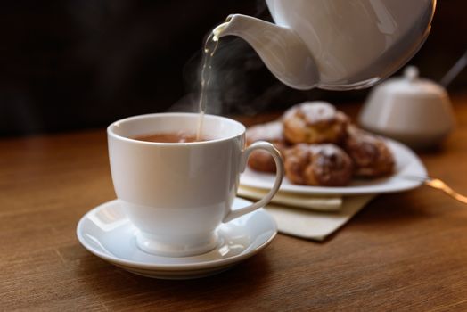 eclairs with custard cream with tea and teapot