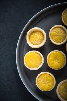 Mini lemon custard tarts on plate, from above