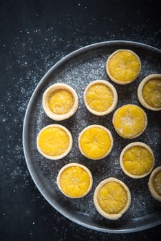 Mini lemon custard tarts on plate, from above