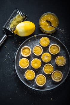 Mini lemon custard tarts on plate, from above