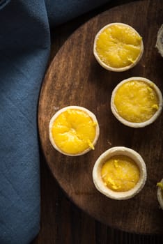 Lemon and custard mini tarts on wooden rustic board on kitchen table