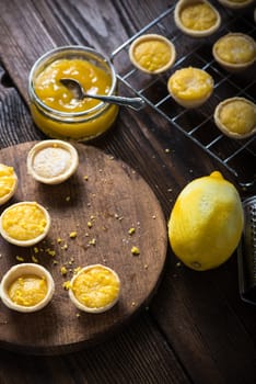 Lemon and custard mini tarts on wooden rustic board on kitchen table