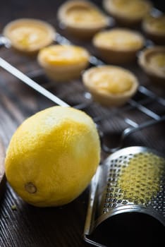 Lemon and custard mini tarts on wooden rustic board on kitchen table