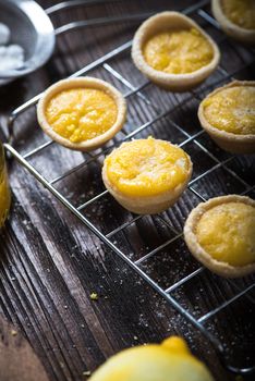 Lemon and custard tarts on cooling tray on wooden rustic table