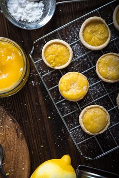 Lemon and custard tarts on cooling tray on wooden rustic table