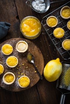 filling lemon and custard mini tarts on wooden rustic board on kitchen table