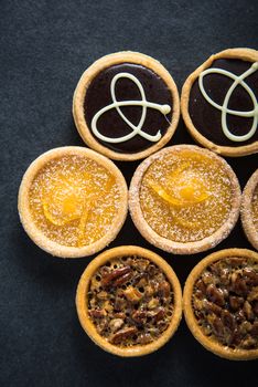 Homemade and hand decorated artisan tarts on dark background
