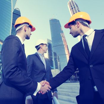 Investor and contractor shaking hands, view from below