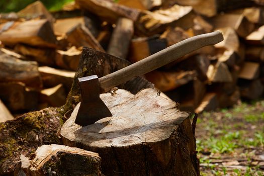 Old ax on a log and firewood in the background