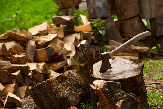 Old ax on a log and firewood in the background