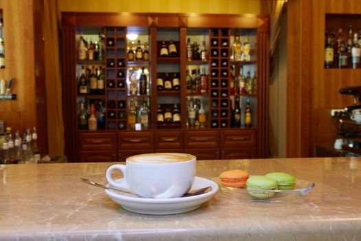 Cup of coffee and coffee break on wood table and macarons and cold water background and nature background and blur background in coffee shop