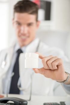 Close-up of cosmetologist showing creme bottle. Selective focus. Focus on foreground, on botle.