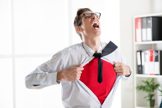 Angry businessman ripping open his shirt and exposing a Superhero red costume underneath. The man is wearing glasses.
