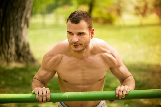 Young muscle Man doing vertical push-ups in the park.