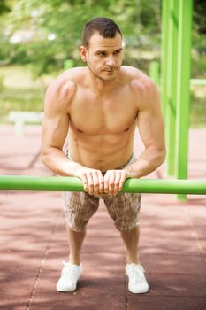 Young muscle Man doing vertical push-ups in the park.