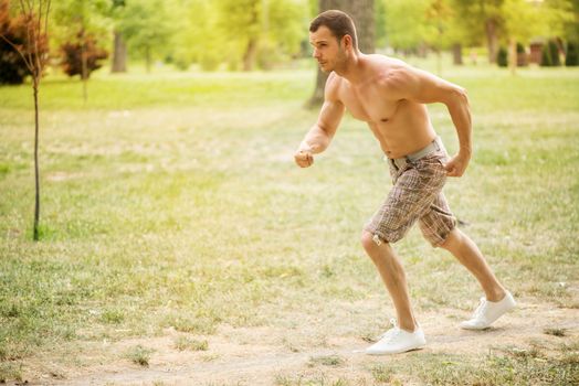 Young muscular man running in the park. 