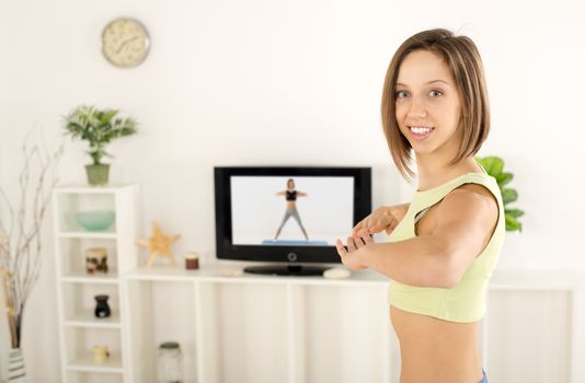Close-up of  a young woman exercising in the room and looking at camera.